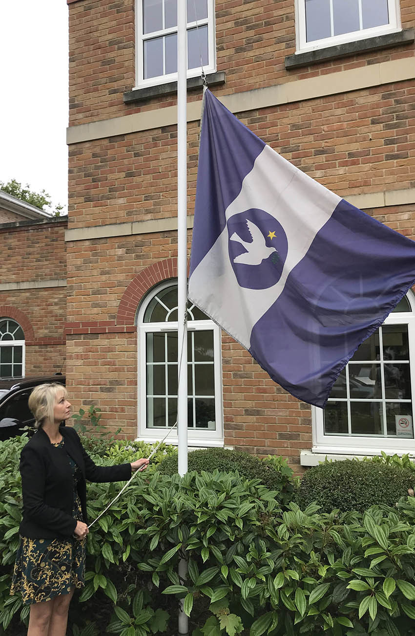 Sailors' Society's acting CEO Sandra Welch lowers the charity's flag in memory of those lost in the HMS Thetis tragedy